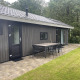 Udendørsbillede af Bos Cottage ved De Thijmse Berg, Holland, med terrasse, bord og stole foran skov.