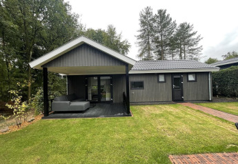 Udendørs billede af Bos Cottage Deluxe på De Thijmse Berg i Holland, med overdækket terrasse og grøn græsplæne.