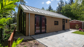 Vista exterior de Eco Cottage Comfort en De Thijmse Berg, Países Bajos, con fachada de madera moderna y patio embaldosado.