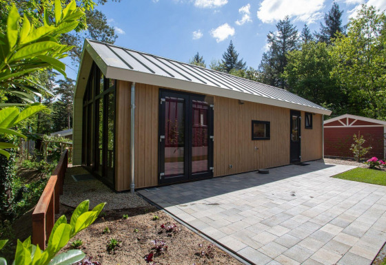 Vista exterior de Eco Cottage Comfort en De Thijmse Berg, Países Bajos, con fachada de madera moderna y patio embaldosado.