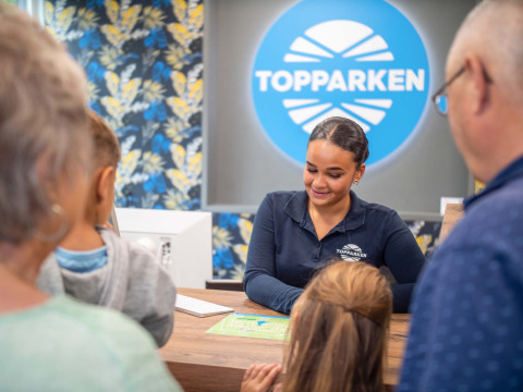 Receptionist accoglie una famiglia al Recreatiepark Beekbergen, villaggio turistico in Gelderland, Paesi Bassi.