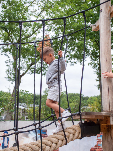 A child crossing a rope bridge at Recreatiepark Beekbergen, a holiday park in Gelderland, Netherlands.