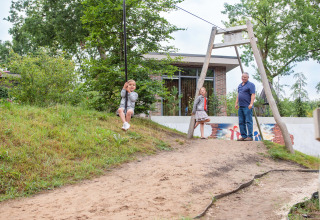 Kinder spielen mit einer Seilrutsche und einem Erwachsenen im Recreatiepark Beekbergen, Gelderland, Niederlande.