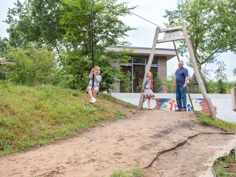 Kinderen op een tokkelbaan met een volwassene bij Recreatiepark Beekbergen, vakantiepark in Gelderland, Nederland.