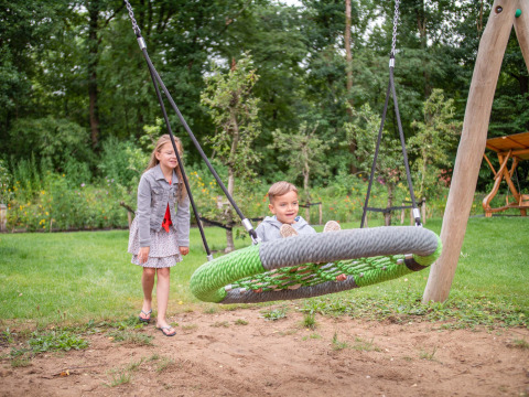 Deux enfants s’amusent sur une balançoire à Recreatiepark Beekbergen, un parc de vacances en Gueldre.