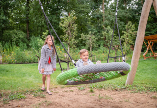 Deux enfants s’amusent sur une balançoire à Recreatiepark Beekbergen, un parc de vacances en Gueldre.