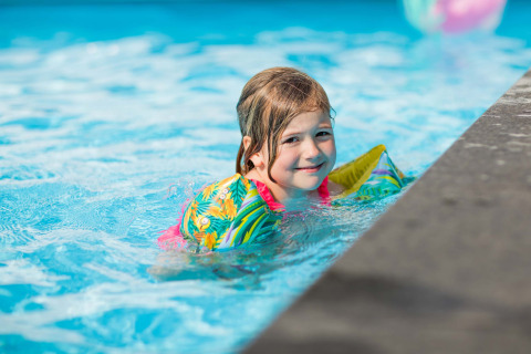 Ein Kind mit bunten Schwimmflügeln schwimmt im Pool im Recreatiepark Beekbergen in Gelderland, Niederlande.