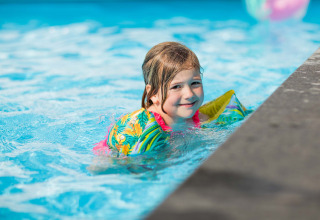 Ein Kind mit bunten Schwimmflügeln schwimmt im Pool im Recreatiepark Beekbergen in Gelderland, Niederlande.
