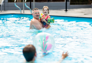 En glad familie leger sammen i swimmingpoolen ved Recreatiepark Beekbergen, Gelderland, Holland.