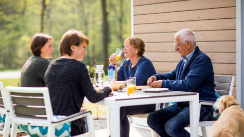 Vier Menschen genießen ein Frühstück im Freien am Tisch im Recreatiepark Beekbergen, Gelderland, Niederlande.