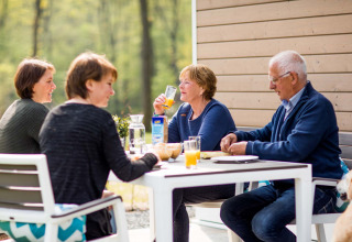 Vier personen ontbijten buiten aan een tafel in Recreatiepark Beekbergen, Gelderland, Nederland.