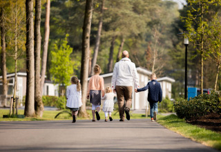 Eine Familie spaziert durch den Recreatiepark Beekbergen Ferienpark in Gelderland, Niederlande, umgeben von Natur.