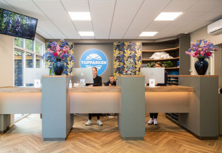 Rezeption im Recreatiepark Beekbergen, Gelderland, Niederlande mit freundlichem Personal und Blumen.