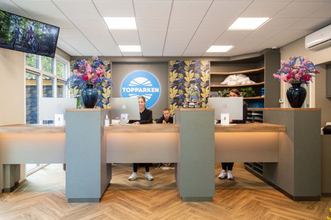 Reception del Recreatiepark Beekbergen in Gelderland, Paesi Bassi, con personale e arredamento moderno.