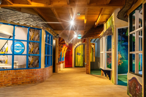 Pasillo interior en Resort Veluwe, Gelderland, Países Bajos, con puertas coloridas y decoración creativa.