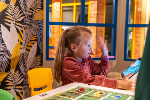 Une fille utilise une tablette dans une salle de jeux colorée au Resort Veluwe, un parc de vacances aux Pays-Bas, à Gueldre.