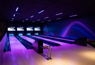 Allée de bowling moderne éclairée en violet au Resort Veluwe, parc de vacances à Gelderland, Pays-Bas, de nuit.