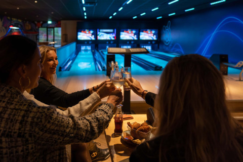 Des amis trinquent avec des boissons et des snacks dans une salle de bowling au Resort Veluwe, Gelderland, Pays-Bas.