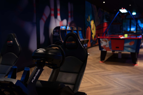 Salle d’arcade au Resort Veluwe, Gueldre, Pays-Bas avec simulateur de course, air hockey et fresques colorées.