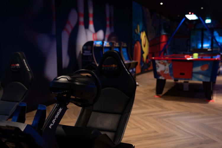 Speelhal bij Resort Veluwe in Gelderland, Nederland met racesimulator, airhockeytafel en kleurrijke muurschildering.