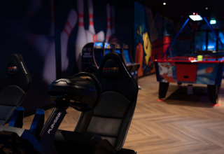 Salle d’arcade au Resort Veluwe, Gueldre, Pays-Bas avec simulateur de course, air hockey et fresques colorées.