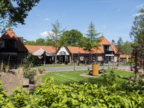 Vista del Resort Veluwe en Gelderland, Países Bajos, con césped, jardines y edificios de tejado rojo.