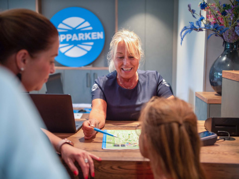 Recepcionista ayuda a huéspedes con un mapa en el mostrador del Resort Veluwe, parque vacacional en Gelderland, Países Bajos.