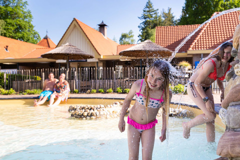 Niños juegan en la piscina infantil con chorros de agua en el Resort Veluwe, parque vacacional en Gelderland, Países Bajos.