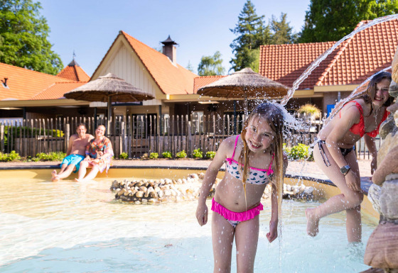 Kinderen spelen in het kinderbad met waterfonteinen bij Resort Veluwe vakantiepark in Gelderland, Nederland.