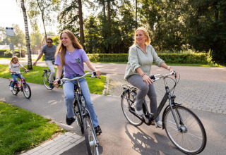 Een vrolijk gezin fietst samen in Resort Veluwe, een vakantiepark in Gelderland, Nederland, omgeven door natuur.