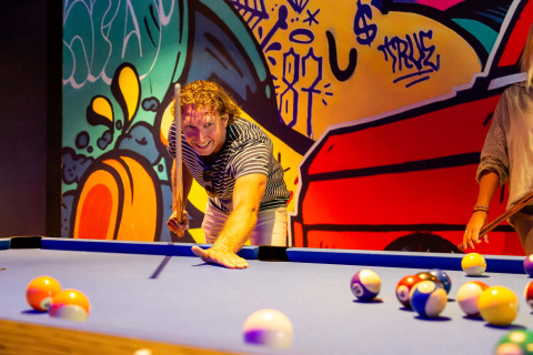 Hombre jugando billar en una sala colorida con mural de graffiti en Resort Veluwe, Gelderland, Países Bajos.