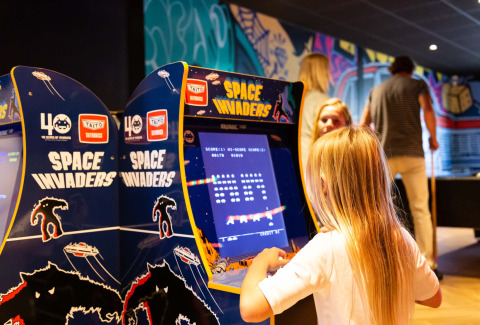 Niña juega en la máquina arcade Space Invaders dentro del Resort Veluwe, en Gelderland, Países Bajos.