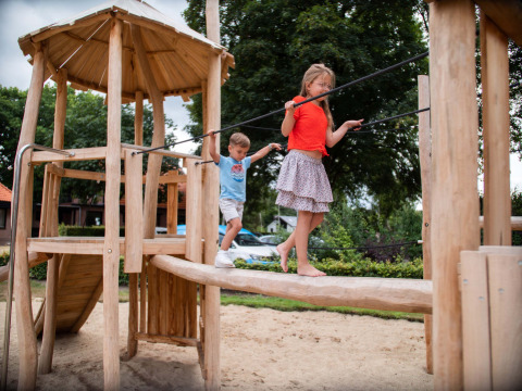 Niños jugando en un parque infantil de madera en Resort Veluwe, parque vacacional en Gelderland, Países Bajos.