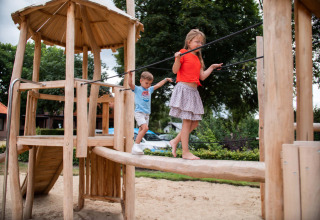 Kinderen spelen op een houten speeltuig in Resort Veluwe, een vakantiepark in Gelderland, Nederland.