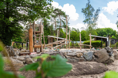 Parque infantil natural con estructuras de madera y rocas en Resort Veluwe, parque vacacional en Gelderland, Países Bajos.