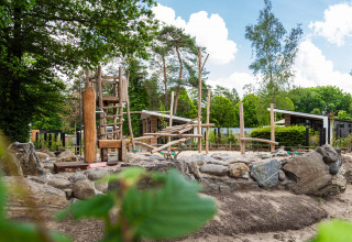 Natuurlijke speeltuin met houten speeltoestellen en keien bij Resort Veluwe vakantiepark in Gelderland, Nederland.