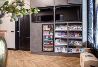 Moderne lounge bij Bospark Ede in Gelderland met tv’s, tijdschriften, kranten en kinderspeelgoed.