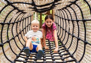 Twee kinderen spelen in een klimtunnel van touw bij Bospark Ede, een vakantiepark in Gelderland, Nederland.