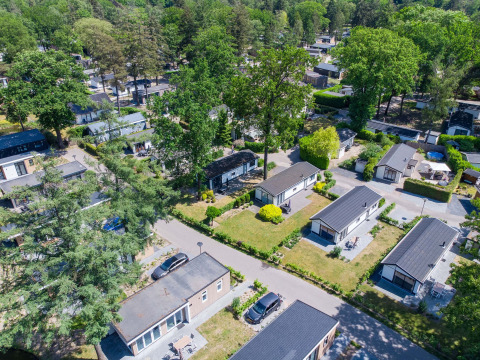 Luchtfoto van vakantiehuisjes omgeven door groen in Bospark Ede, een vakantiepark in Gelderland, Nederland.