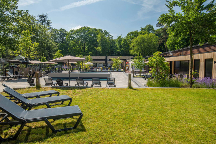Außenbereich mit Liegestühlen und Sonnenschirmen im Bospark Ede, Ferienpark in Gelderland, Niederlande.