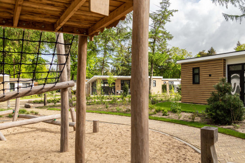 Parque infantil con estructura para trepar y cabañas modernas en Bospark Ede, Gelderland, Países Bajos.