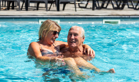 Pareja mayor disfruta de un día soleado en la piscina de Bospark Ede, un parque vacacional en Gelderland.