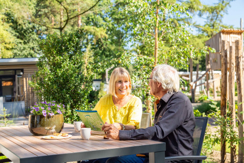 Two seniors enjoy coffee and cookies outside at Bospark Ede holiday park in Gelderland, Netherlands.