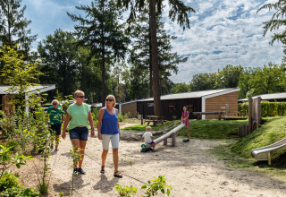 Vakantiepark Bospark Ede in Gelderland, Nederland, met wandelende volwassenen en spelende kinderen buiten.
