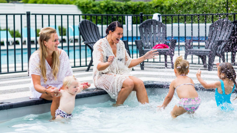 Deux femmes et trois jeunes enfants jouent près de la piscine au Bospark Ede, un parc de vacances en Gueldre, Pays-Bas.