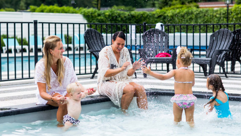 Dos mujeres y tres niños disfrutan juntos en la piscina infantil de Bospark Ede en Gelderland, Países Bajos.