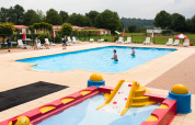 Piscina per bambini con scivolo e lettini al Camping La Colline, parco vacanze nel Lussemburgo belga.