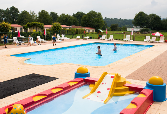 Piscina per bambini con scivolo e lettini al Camping La Colline, parco vacanze nel Lussemburgo belga.
