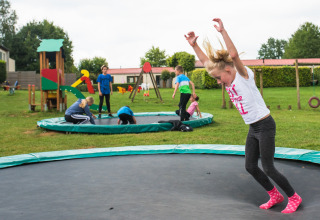 Bambini giocano su trampolini interrati e parco giochi a Camping La Colline, Belgio, Lussemburgo.