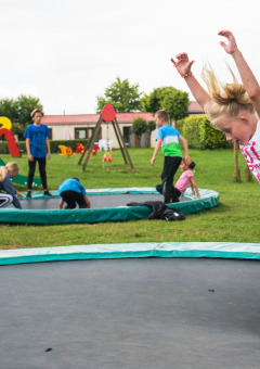 Children play on sunken trampolines and a playground at Camping La Colline holiday park in Belgium, Luxembourg.